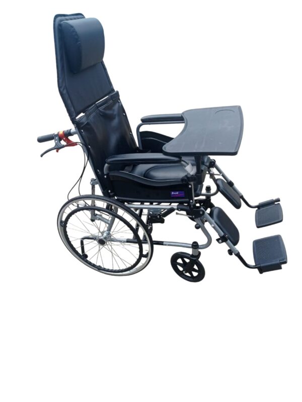 The wheelchair in the image is a high-back manual wheelchair, identified as a Wollex W213 or similar model, with several key features. Adjustable and Reclining Design: The wheelchair has a high backrest that can be reclined and a headrest for support. The footrests are also adjustable and can be raised. Removable Components: The armrests and footrests are detachable, which can make it easier for the user to transfer in and out of the chair. Tray: A removable tray is attached to the armrests, providing a surface for activities or meals. Braking System: The wheelchair includes a companion brake system, which allows an attendant to control the chair's speed and stop it. Durability and Portability: The frame is made of steel, and the wheelchair is foldable for easy storage and transportation.